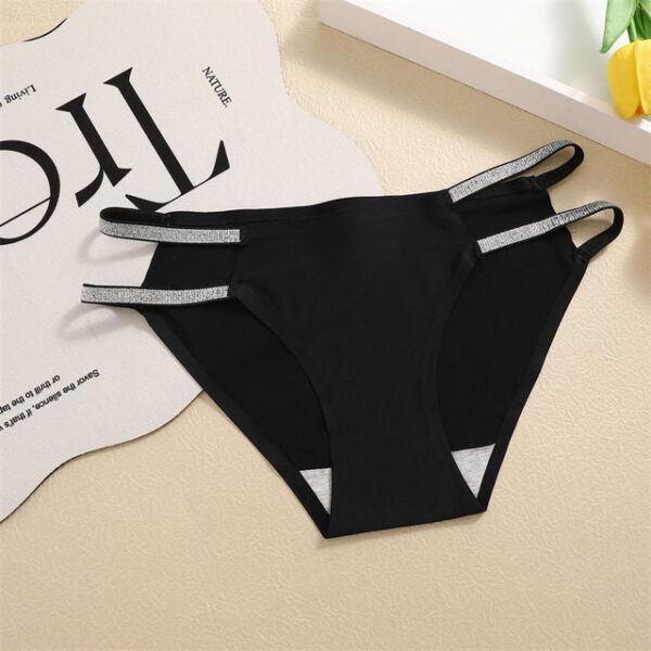 Black bikini bottom with silver straps on a beige surface