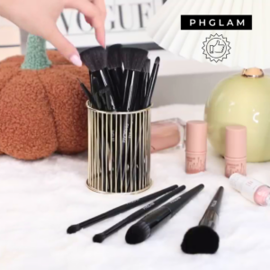 Makeup brushes in a holder with 'PHGLAM' branding on a decorative background